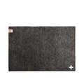 Baabuk dark grey rectangular felted wool table mat with a small Swiss cross detail and brand tag.