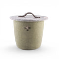 Baabuk small khaki felted wool basket with a lid, brown leather handle, and Swiss cross cutout detail.