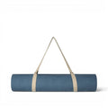 Tapis de yoga Baabuk en laine feutrée bleu clair, enroulé et muni d'une sangle de transport en coton beige, sur fond blanc.