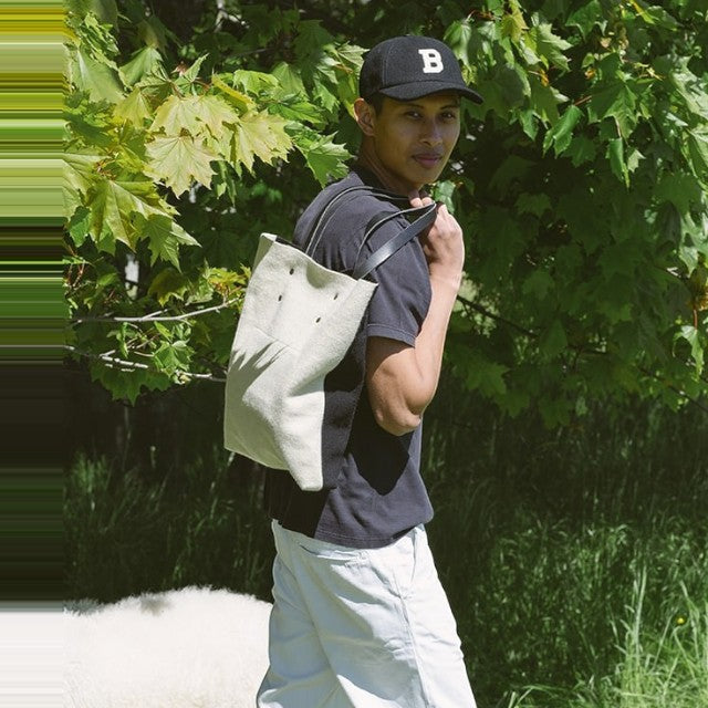 Man wearing a Baabuk Blacknose reversible wool and leather tote bag outdoors in a natural setting.