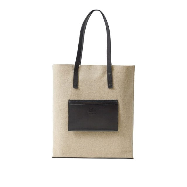 Baabuk Blacknose reversible tote bag in beige wool with black leather handles and front pocket.
