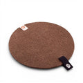 Baabuk round brown felted wool trivet hot plate with a small leather hanging strap on a white background.