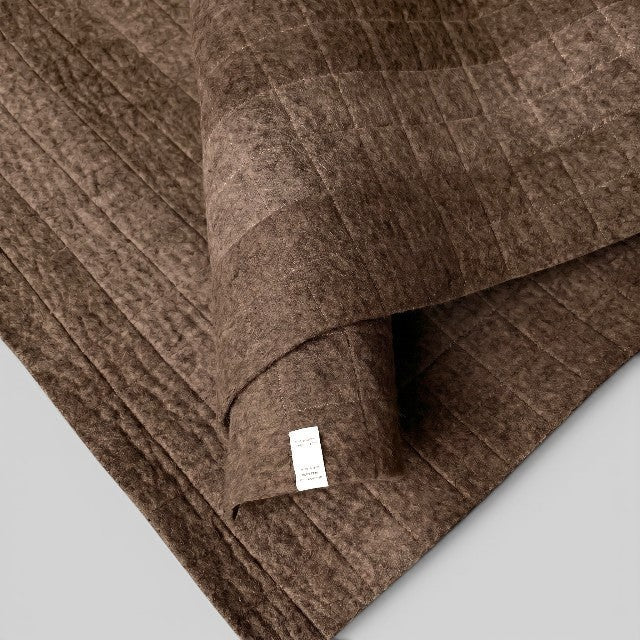 Baabuk brown felted wool yoga mat with quilted stitching and a soft textured surface for a natural practice.