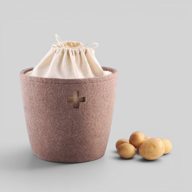 Baabuk large brown felted wool basket with a Swiss cross cutout and cream drawstring liner, holding potatoes.