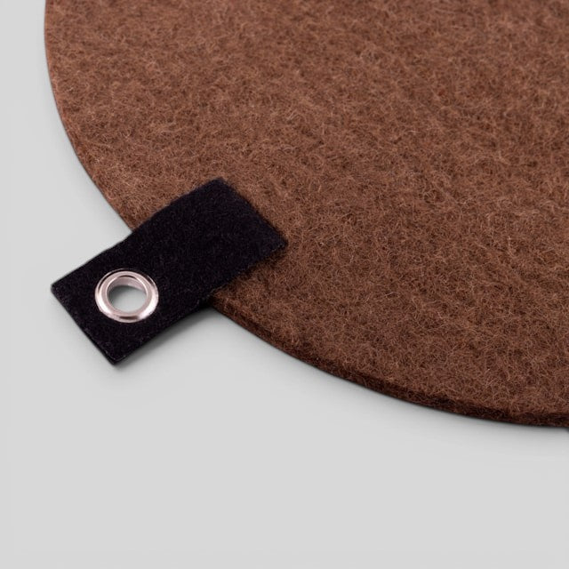 Baabuk brown felted wool trivet hot plate with a black leather hanging strap and metal grommet.