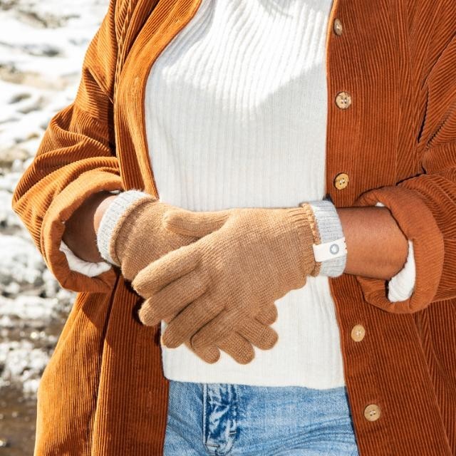 Baabuk camel reversible baby alpaca wool gloves with grey cuffs worn by a person in a corduroy shirt.