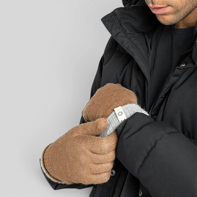 Baabuk camel reversible baby alpaca wool gloves worn by a man in a black winter jacket