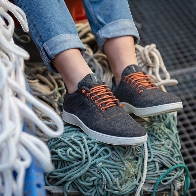 Baabuk Classic Wooler sneakers in grey wool with bright orange laces, worn with blue jeans on a nautical rope background