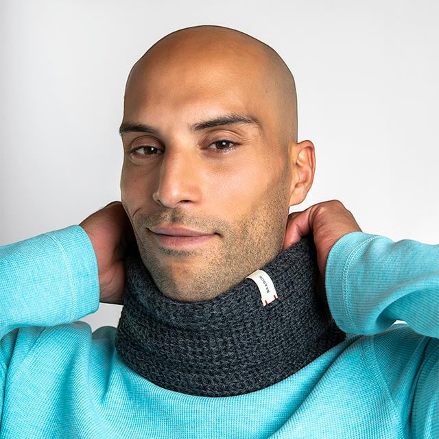 Man wearing a dark grey Baabuk infinity scarf made from soft baby alpaca wool against a light background.