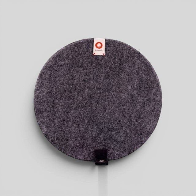Baabuk dark grey round felted wool trivet with a leather strap for heat-resistant kitchen surface protection.