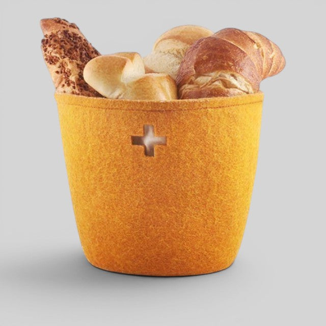 Baabuk large honey yellow felted wool basket with a Swiss cross cutout, filled with assorted bread rolls.