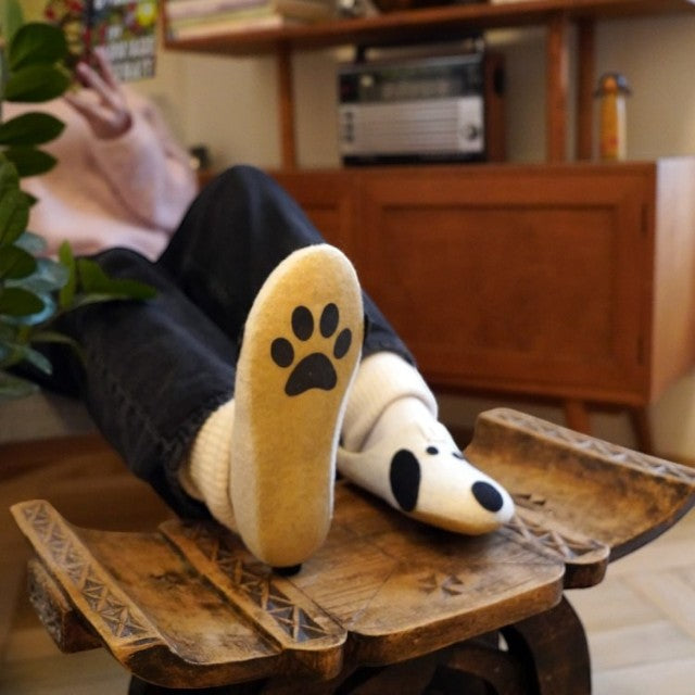 Baabuk Kanga Woof slippers featuring a white wool upper with dog-inspired spots and a paw-print natural latex sole.