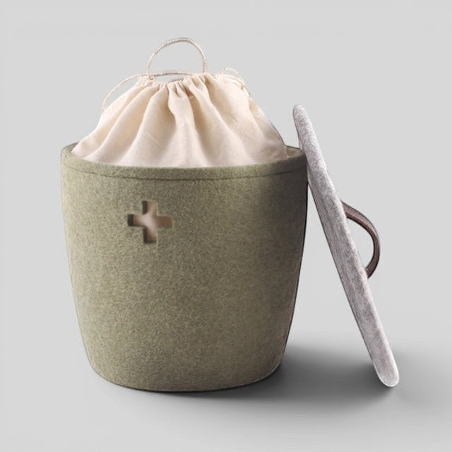Baabuk small khaki felted wool basket with a Swiss cross cutout, cream fabric liner, and a matching wool lid.
