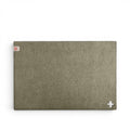 Baabuk khaki felted wool table mat with a small Swiss cross cutout and branded tag on a white background.