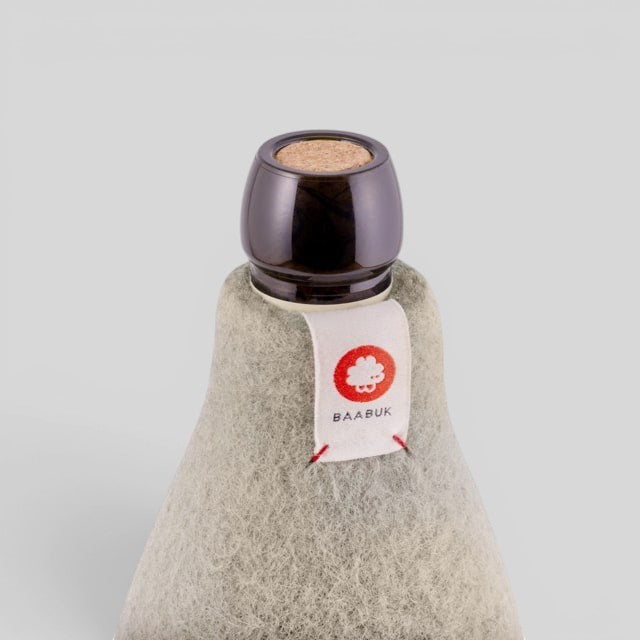 Baabuk khaki wool bottle cover with natural insulation and a branded fabric tag on a grey background