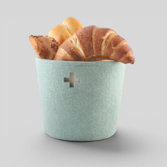 Baabuk small light blue felted wool basket with Swiss cross detail, filled with fresh bread and croissants.
