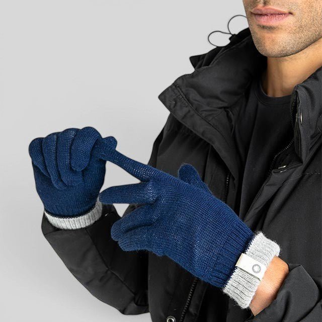 Baabuk marine blue reversible baby alpaca wool gloves worn by a man in a black winter jacket.