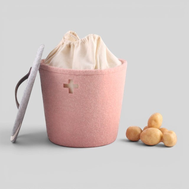 Baabuk small pink felted wool storage basket with a Swiss cross cutout, leather handle, and cream fabric liner.