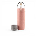 Baabuk pink wool wine cooler with a leather strap and a matching grey wool base, holding a wine bottle.