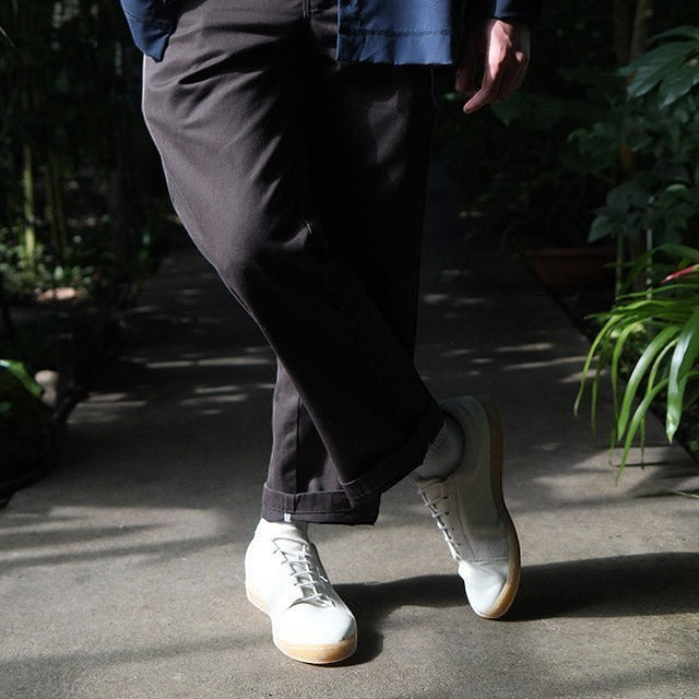 Baabuk Shunya Wooler white sustainable wool sneakers worn by a person in dark trousers outdoors