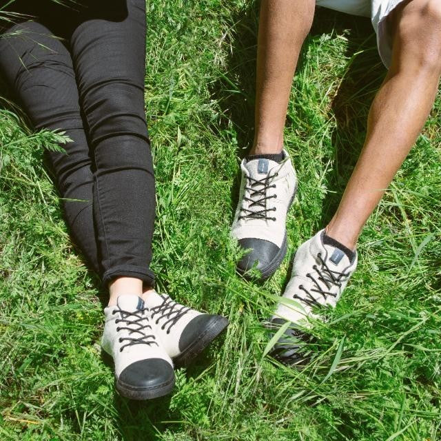 Two people wearing Baabuk Sky Wooler Blacknose sneakers with off-white wool and black rubber toes in green grass.