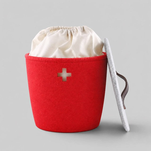 Baabuk small red felted wool basket with a Swiss cross cutout, white fabric liner, and a grey lid with leather strap.