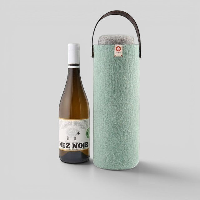 Baabuk turquoise wool wine cooler with a brown leather strap, shown next to a bottle of white wine.