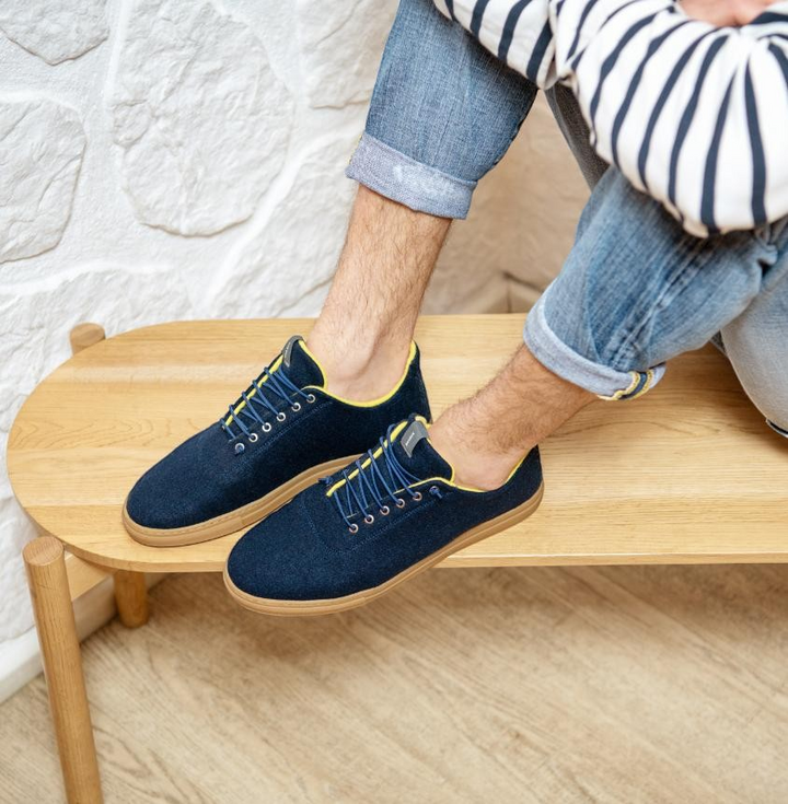 Baabuk Urban Wooler navy blue wool sneakers with yellow trim and gum rubber soles worn by a man in jeans