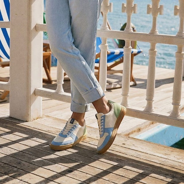 Baabuk Urban Wooler Wonderland sneakers in blue, cream, and green wool with rubber soles worn on a wooden deck.