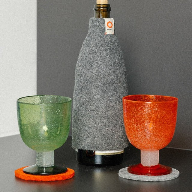 Baabuk grey wool insulated bottle cover with a small brand tag, displayed with two textured glass goblets.