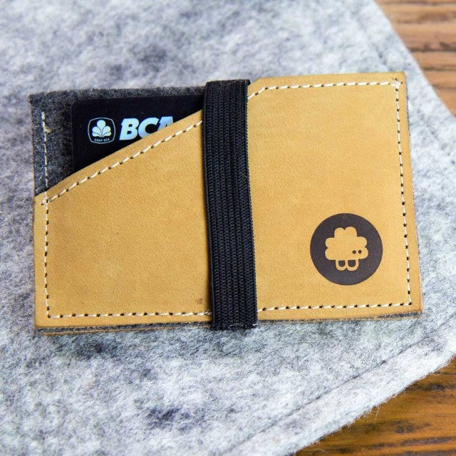Baabuk slim wallet in grey wool and tan leather with a black elastic strap and logo, holding a credit card.