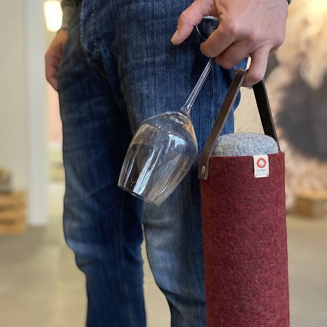 Seau à vin en laine bordeaux Baabuk avec lanière en cuir, contenant un verre à vin.