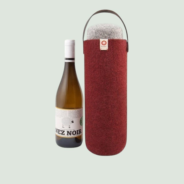 Un seau à vin en laine rouge Baabuk muni d'une poignée en cuir, à côté d'une bouteille de vin blanc.
