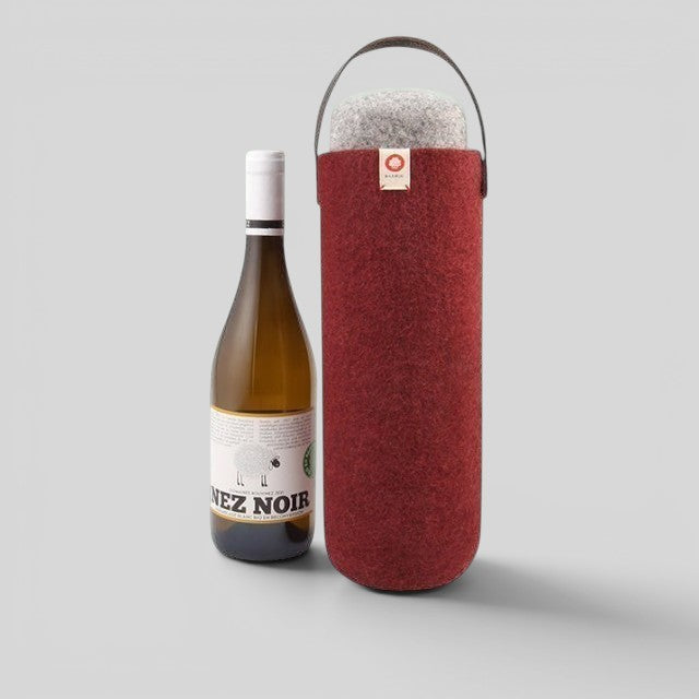 Baabuk red wool wine cooler with leather handle next to a bottle of white wine.