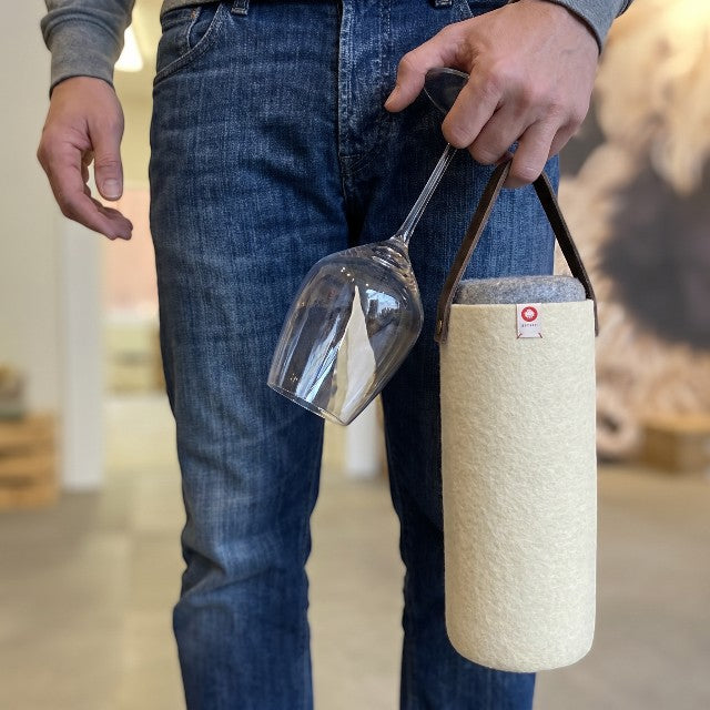 Baabuk natural wool wine cooler in cream with leather strap, holding a wine bottle. Perfect for picnics.