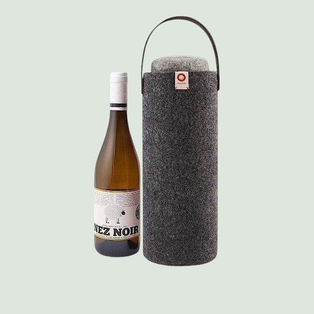 Baabuk dark grey wool wine cooler with leather handle next to a bottle of white wine.