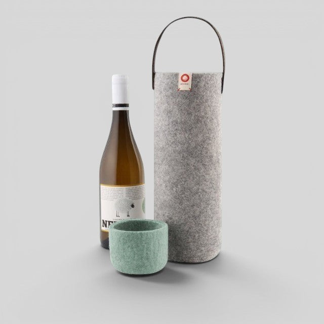 Baabuk light grey wool wine cooler with leather handle, next to a bottle of white wine and a green wool coaster.