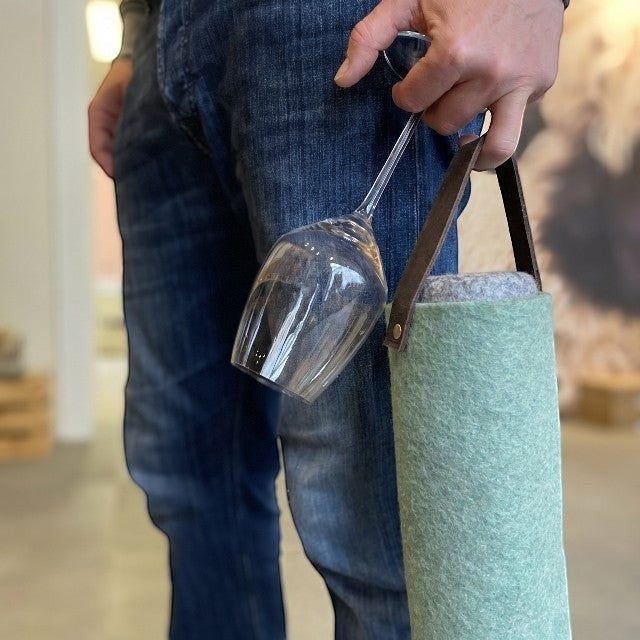 Baabuk turquoise wool wine cooler with leather strap, holding a wine glass.