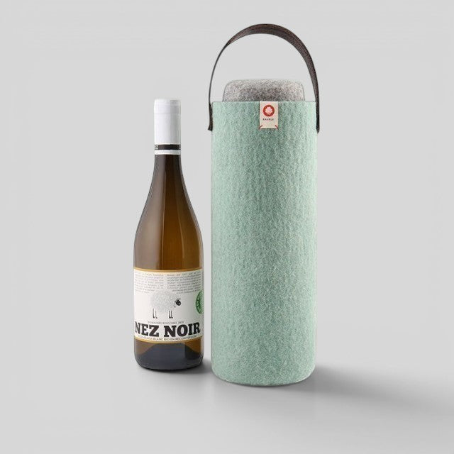 Baabuk turquoise wool wine cooler with leather handle next to a bottle of white wine.