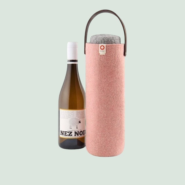 Baabuk blush pink felt wine bottle carrier with faux leather handle and matching coaster, next to a bottle of white wine.